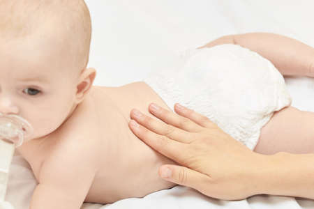 Newborn boy, mother hand. Infant mom massage. funny children change diaper. Home napkin.の写真素材