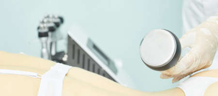 Cavitation rf body treatment. Female ultra sound lipo machine. Spa contouring. Doctor hands.の写真素材