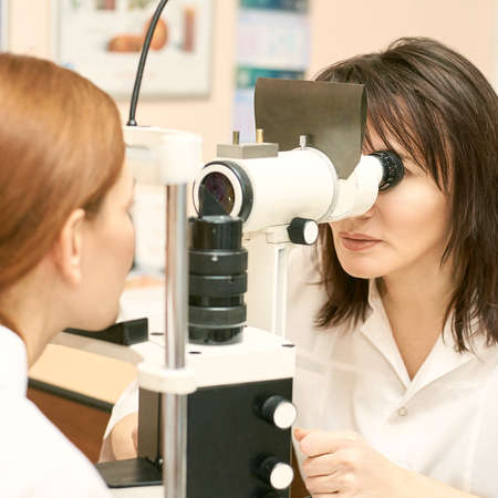 ophthalmologist doctor in exam optician laboratory with female patient. Eye care medical diagnostic. Eyelid treatmentの写真素材