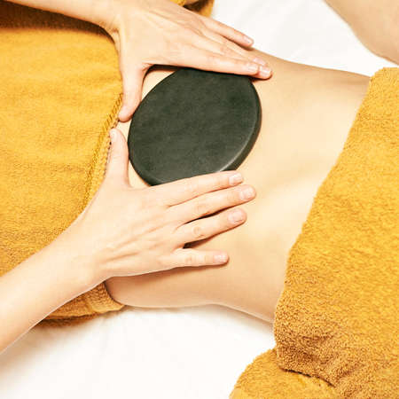 body stone massage. Hot rock masseur. Girl at salon with doctor hands. Relax spa resort.の写真素材