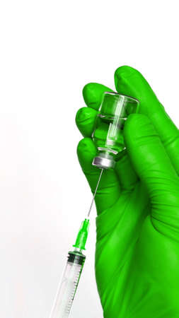 Person in green glove hold vaccine bottle with syringe. Injection pharmacy concept. Medical nurse therapy. People hand health science. Vertical bannerの写真素材