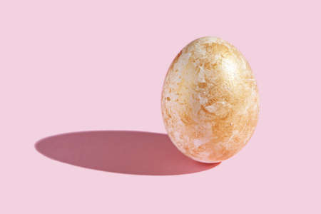 One decorative egg with hard shadow. Art easter concept. Single decorated gold color. Pink...
