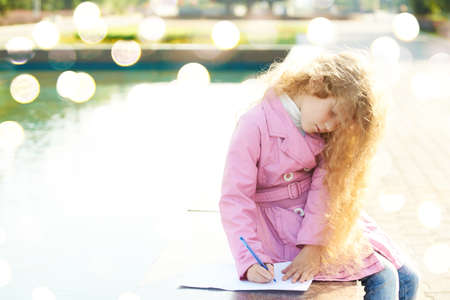 Little girl draw outdoor. Miracle bokeh background. Kid play alone. Social distance quarantine. Work...