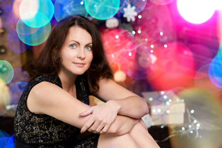 Pretty young woman. Lights bokeh background. Female portrait. Happy emotions. Christmas glitter concept. Horizontal. Girl stay home at quarantine. American lifestyle. Copyspaceの写真素材