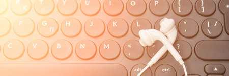 Podcast record. headphone at computer keyboard. Audiobook and podcasting. Audio technology. Home school teaching. Edit episode. Flatlay earpods. Horizontla bannerの写真素材