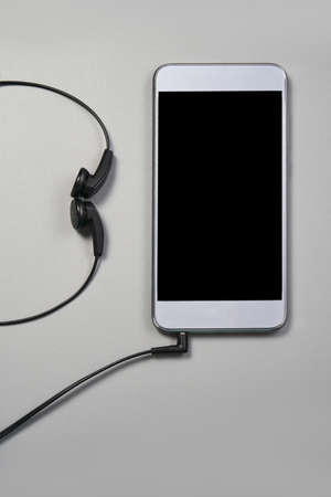 Podcast concept. Phone and earphones. Grey background. Music top view. Audio technology. Hipster...