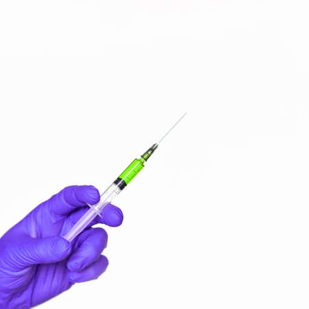 Doctor hand hold syringe in purple glove. Injection yellow vaccine concept. Medical injector for...