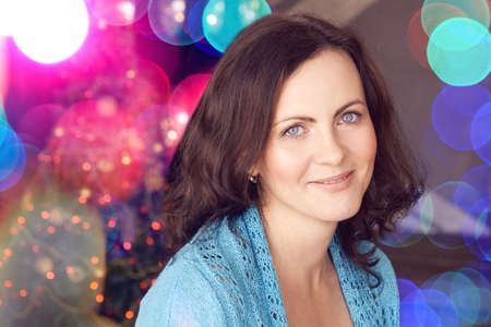 Pretty young woman. Lights bokeh background. Female portrait. Happy emotions. Christmas glitter...