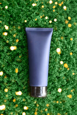 Dark blue tube of cream. Lying on the green moss. View from above. Daily home care for face and body skin. Sunscreen. Personal hygiene routine. For men and guys. Template for text. Copyspace. Mockupの写真素材