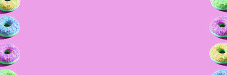 Doughnut frame. Purple, green, pink, lime color. Tasty unhealthy round food. rose background. Many...
