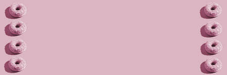 Doughnut frame. Pink color. Tasty unhealthy round food. rose background. Many donuts. Berry bake snack. One size. Breasfast with coffee and snack. Lots dessert. Horizontal banner. Copyspaceの写真素材