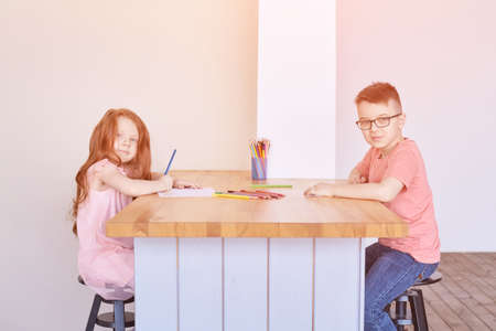 Little boy and girl drawing. Closed Locking Exercise. Homemade routine. School lessons. Write pencil on piece of paper. Kindergarten study. Elementary preschool. Man kid studentの写真素材