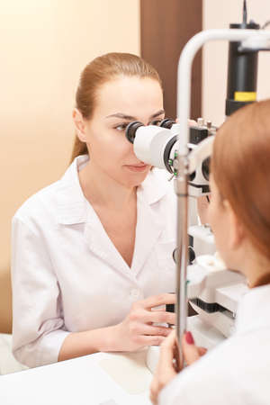 ophthalmologist doctor in exam optician laboratory with female patient. Eye care medical diagnostic. Eyelid treatmentの写真素材