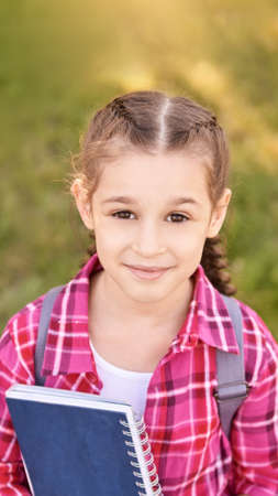Young schoolgirl with backpack. Lifestyle going to classroom. Outdoor autumn park. Children learn...