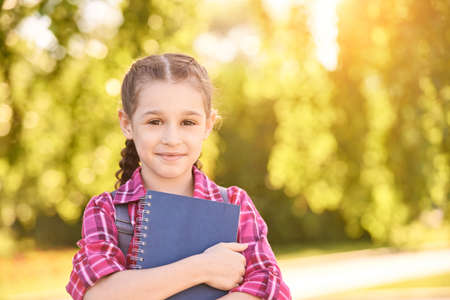 Young schoolgirl with backpack. Lifestyle going to classroom. Outdoor autumn park. Children learn smart. Street student. Happy preschool kid. Back to schoolの写真素材