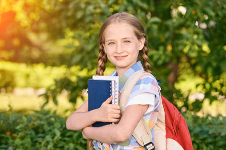 Young schoolgirl with backpack. Lifestyle going to classroom. Outdoor autumn park. Children learn...