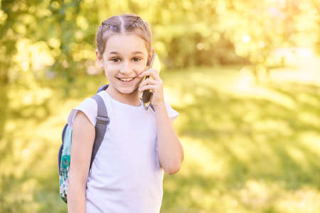Cute little girl talking. Hold phone near face. Young woman smile. Looking at camera. Outdoor...
