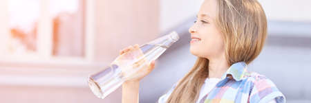 Little girl holding water bottle. Outdoor training. Thirsty. Glass drink. Summer time. Ecology...