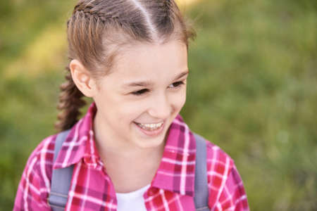 Young schoolgirl with backpack. Laugh. Lifestyle elementary school. Funny girl. Outdoor autumn park....