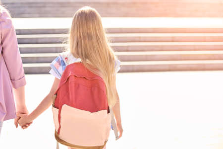 Little girl hold mother hand. Back to school.の写真素材