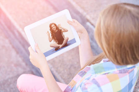 Girl looking at tablet outdoor background.