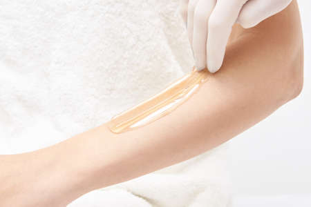 Hot hair removal depilation. Female skin routine. Sugar bodycare. Wax correction. Professional cosmetologist help girl. Sugaring bodycare cosmetics. Horizontal banner with copyspaceの写真素材