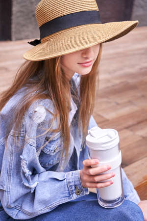 Pretty girl with eco coffee cup. Drinking beverage outdoors. Reusable lifestyle. Staycation concept. Responsible travel. Local vacation. Go green young hipster. City backgroundの写真素材