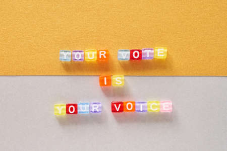 Colorful cube of lettering Your Vote is Your Voice on gold and silver