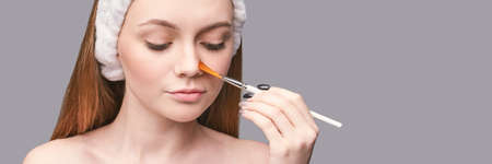 Facial peeling. Pretty girl with cosmetology brush. Anti acne mask. Home skin care routine....