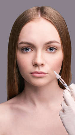 Closeup of rejuvenation lip. Beauty female face. Doctor hands in medicine glovesの写真素材