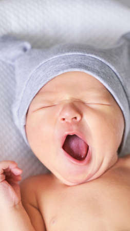 Tiny newborn in hat, Closed eyes and yawn