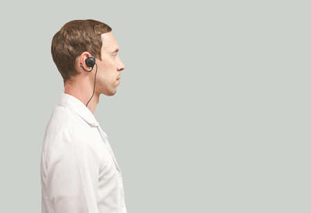 Male doctor headphones. Studio Medicine portrait. Clinic online help. Health support call. Telemarketing agent microphone. Multi language translator. Telemedicine equipment. Profile view. Copyspaceの写真素材