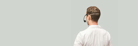 Male doctor with headphones. Studio Medicine portrait. Clinic online help. Health support call. Telemarketing agent microphone. Multi language translator. Telemedicine equipment. Back view. Copyspaceの写真素材