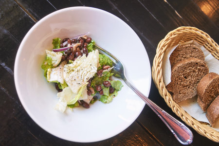 Kidney beans health salad. Dark table and white plate. Cafe menu. Green leaves and cheese fitness dinner. Organic vegetable diet. Black bread bowl. Vegan product. Fast eat. Flatlay. Top Viewの写真素材
