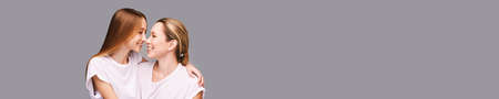 Mother and daughter studio portrait. Grey background. Smiling people. Two female person family....