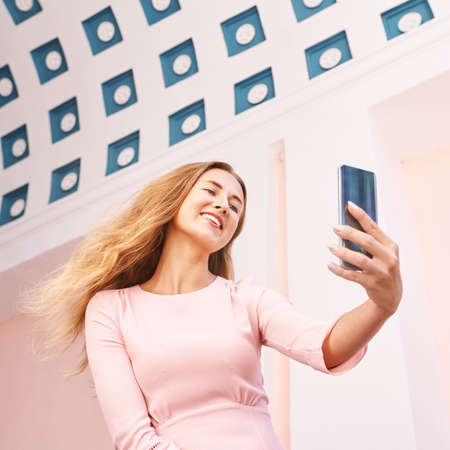 Young woman doing self portrait outside. City vacation portrait. Blogger selfie video.