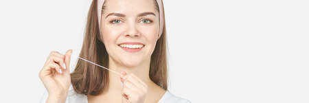 Young woman holding teeth floss. Dental health care concept. Beauty smiling face. Adult mouth everyday routine. Toothache cleaning. Orthodontist whiteningの写真素材