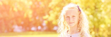 Little girl. Autumn yellow and green colors. Backyard nature. Female child portrait. Happy people. Model posing at park. Curly hairの写真素材