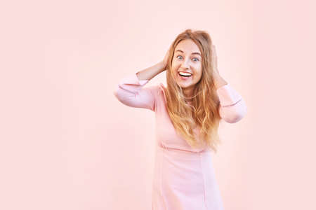 Pretty young woman amazed by sale news. Happy female person outdoors. Summer cute portrait. Lady blonde long hair. Cute adult student at town. Pink background. Copyspace. Wow female emotionの写真素材