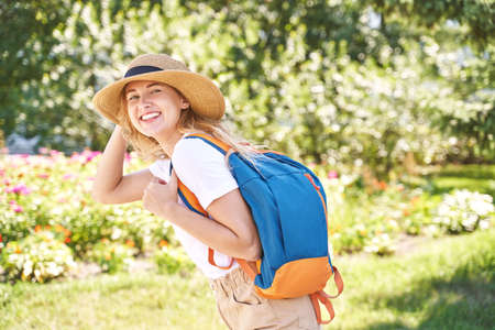Young woman with bright backpack. Local tourist. Summer sunny day. Green background. Staycation...