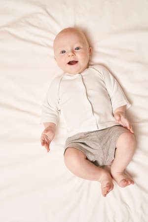 Cute small boy lying at bed. Childhood concept. Light background. Smiling child. Happy emotion....