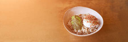 reen buckwheat with poached egg and avocado. Lifestyle Modern plate with porridge. Cereal breakfast...