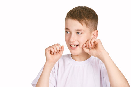 Children portrait in white t-shirt. Studio isolated concept. Boy usin toooth floss. Orthodontist...
