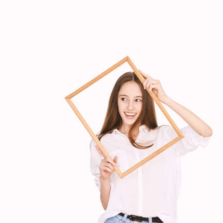 Pretty girl indoor portrait. Light background. Female teenager person. Long brow hair. Out of frame concept. Success modern people. Happy smile. Positive emotionの写真素材