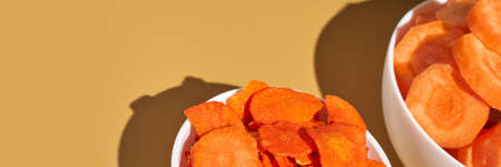 Crispy dried food. Organic tasty chips. Homemade snacks. Sliced carrot. Healthy vegetables. Orange pile Trend natural dish. Horizontal banner. Copyspaceの写真素材