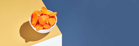 Crispy dried food. Organic tasty chips. Homemade snacks. Sliced carrot. Healthy vegetables. Orange pile Trend natural dish. Horizontal banner. Copyspaceの写真素材