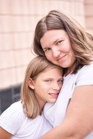 Mother hug teenage daughter. Outdoor family portrait. Two person together. Happy positive feelings. Casual tshirt. Motherhood lifestyle. Parent relationshipの写真素材
