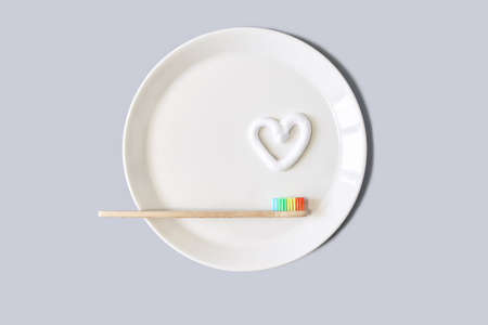 Ecology toothbrush on grey background. Brush on plate. Breakfast concept. Sustainable mouth product....