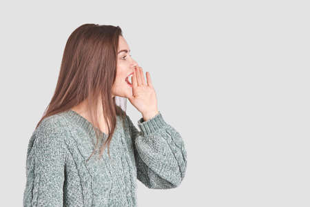 Pretty young woman gesture. Studio portrait. Female person. Home grey sweater. Isolated background....
