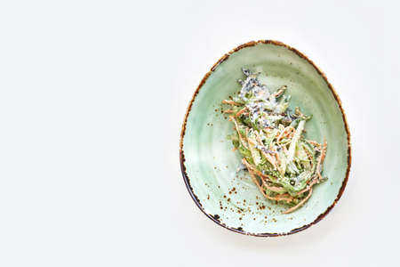 Asian wakame salad. Bowl on kitchen table. Modern dishes. Carrot, cucumber and mayonnaise dinner. Chuka herbsの写真素材